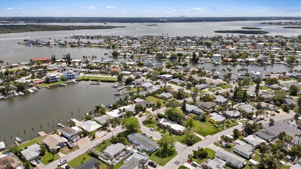 An aerial view shows a coastal neighborhood with houses, canals, and a large bay — 14033 E PARSLEY DRIVE, MADEIRA BEACH, FL