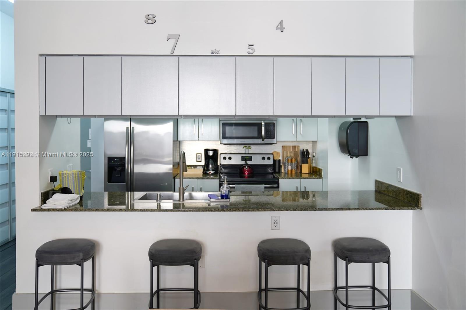 A kitchen features a granite breakfast bar, stainless steel appliances, and gray cabinetry — 1200 Brickell Bay Dr # 1406, Miami FL 33131, MIAMI, FL