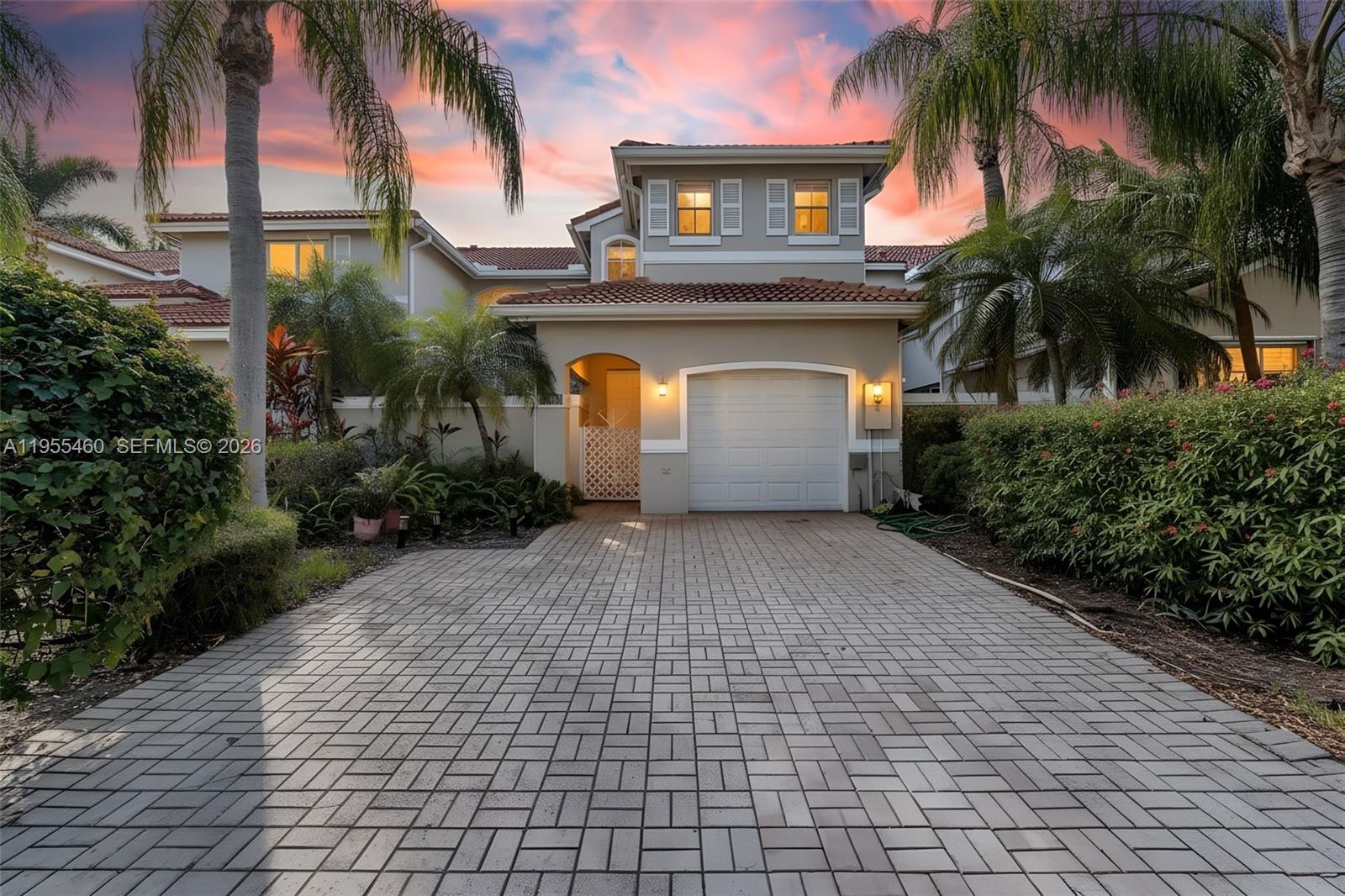 A two-story house with a paved driveway, a single-car garage, and palm trees at sunset — 1120 Cliffrose St, Hollywood FL 33019, HOLLYWOOD, FL