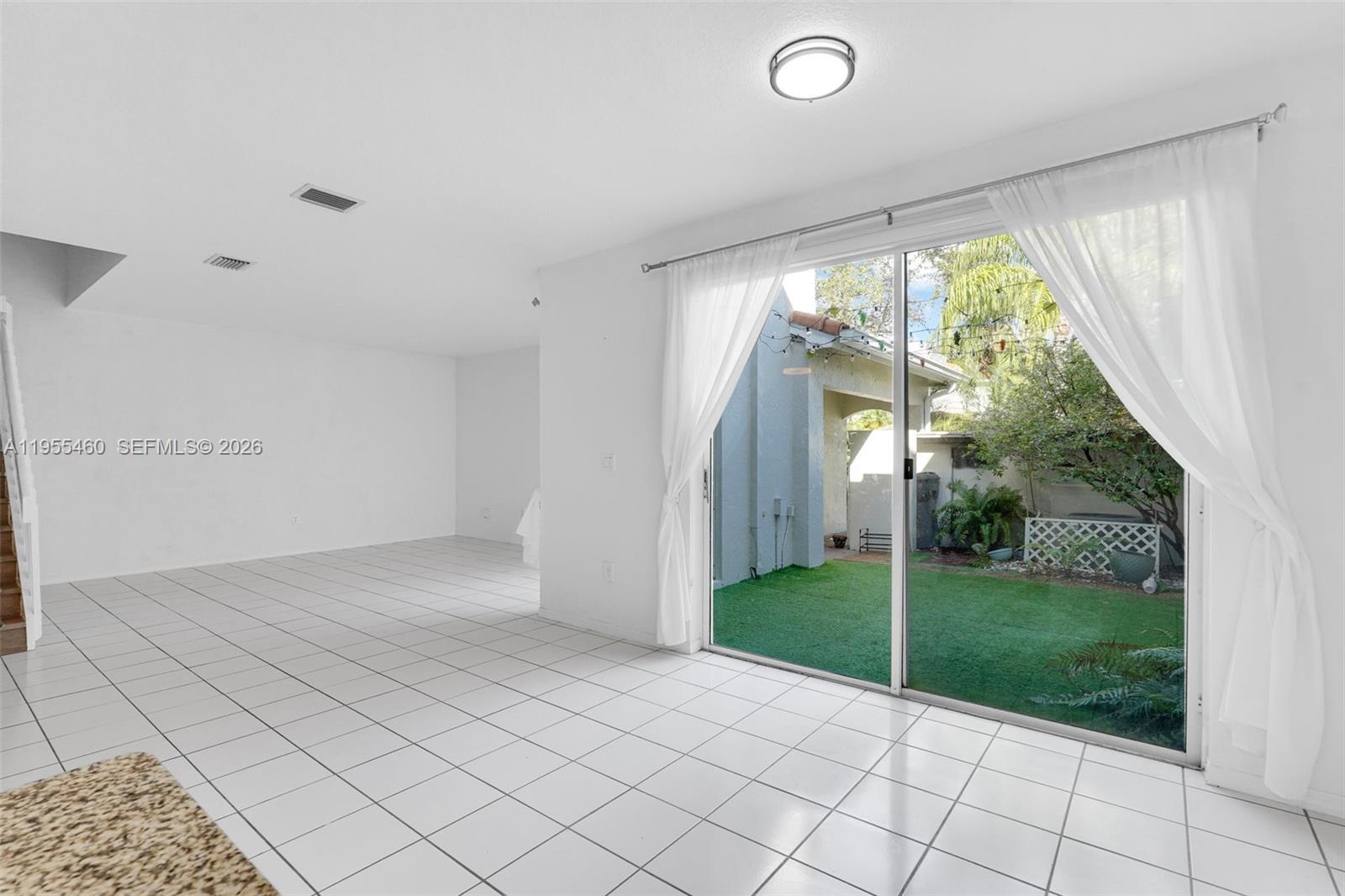 A bright living room with white tile floors features a sliding glass door to a patio — 1120 Cliffrose St, Hollywood FL 33019, HOLLYWOOD, FL