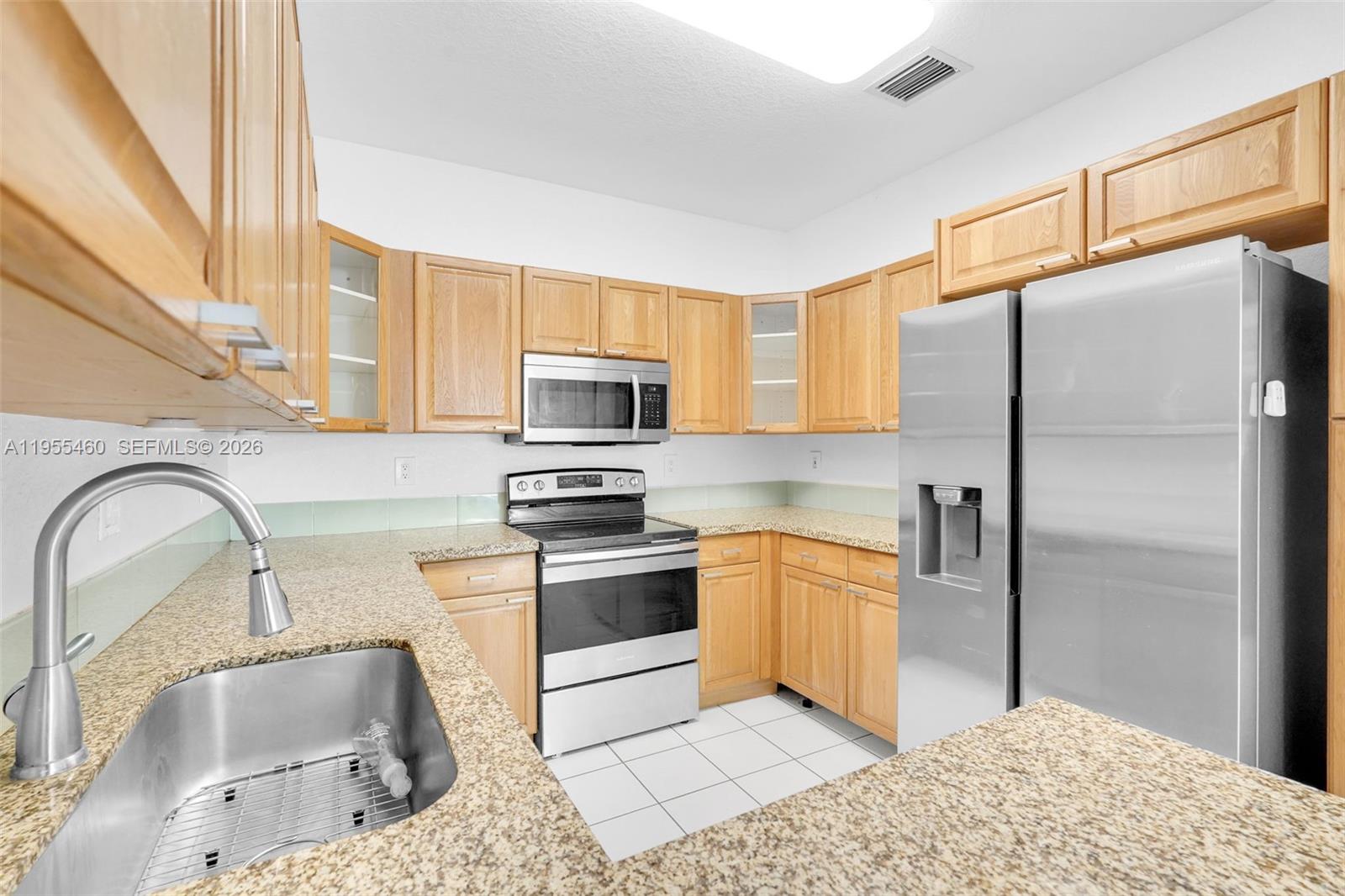 A kitchen features light wood cabinets, granite countertops, and stainless steel appliances — 1120 Cliffrose St, Hollywood FL 33019, HOLLYWOOD, FL