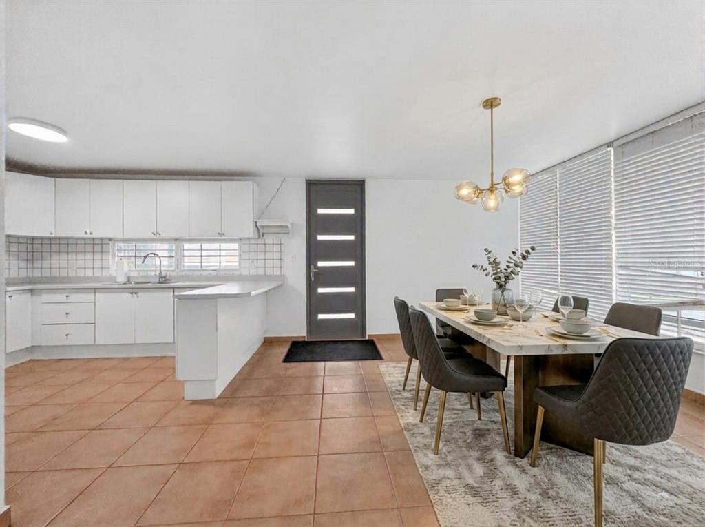 A kitchen and dining area featuring white cabinets, tile flooring, and a modern light fixture — F-23 TOPACIO ST. URB PASEO REAL, DORADO, PR