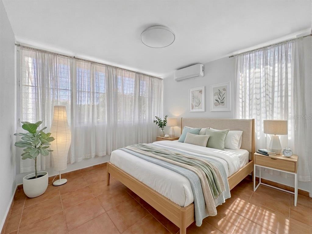 A bedroom features a bed with light-colored linens, tile flooring, and floor-to-ceiling sheer curtains — F-23 TOPACIO ST. URB PASEO REAL, DORADO, PR