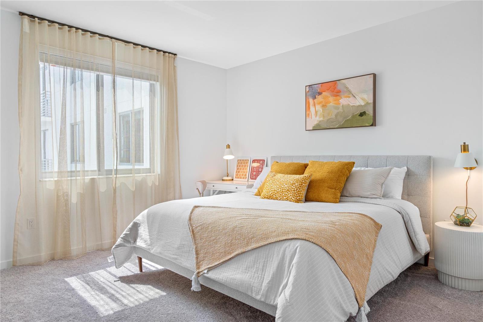 A bright bedroom features a gray upholstered bed, yellow accent pillows, and sheer window curtains — 200 NE 1st Avenue # 1027, Pompano Beach FL 33060, POMPANO BEACH, FL