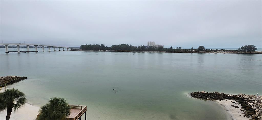 An elevated view of a calm bay with a bridge, sandy shoreline, and palm trees — 675 S GULFVIEW BOULEVARD UNIT 606, CLEARWATER BEACH, FL