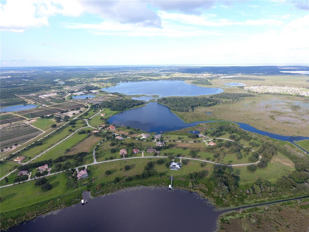 An aerial view shows several houses situated on a grassy landscape between two large lakes — Lot 39 ROYAL PALM DRIVE, GROVELAND, FL