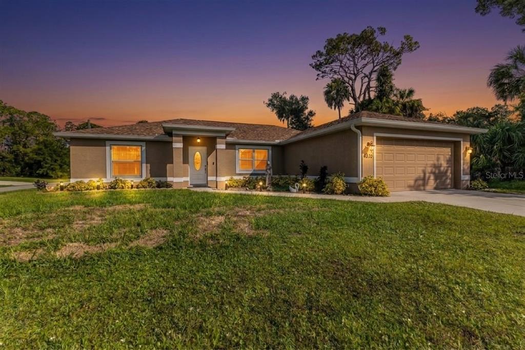 A single-story house with a tan stucco exterior, a two-car garage, and a landscaped yard — 4323 MICHALER STREET, NORTH PORT, FL