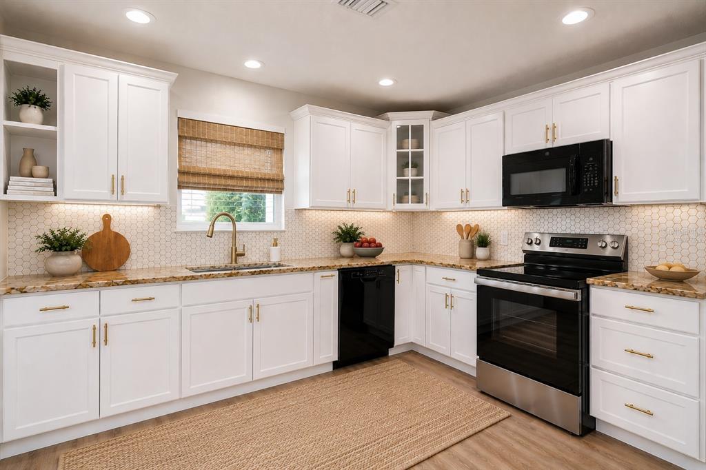A bright kitchen features white cabinets, granite countertops, a black appliance suite, and a woven rug — 12928 KINGS LAKE DRIVE, GIBSONTON, FL