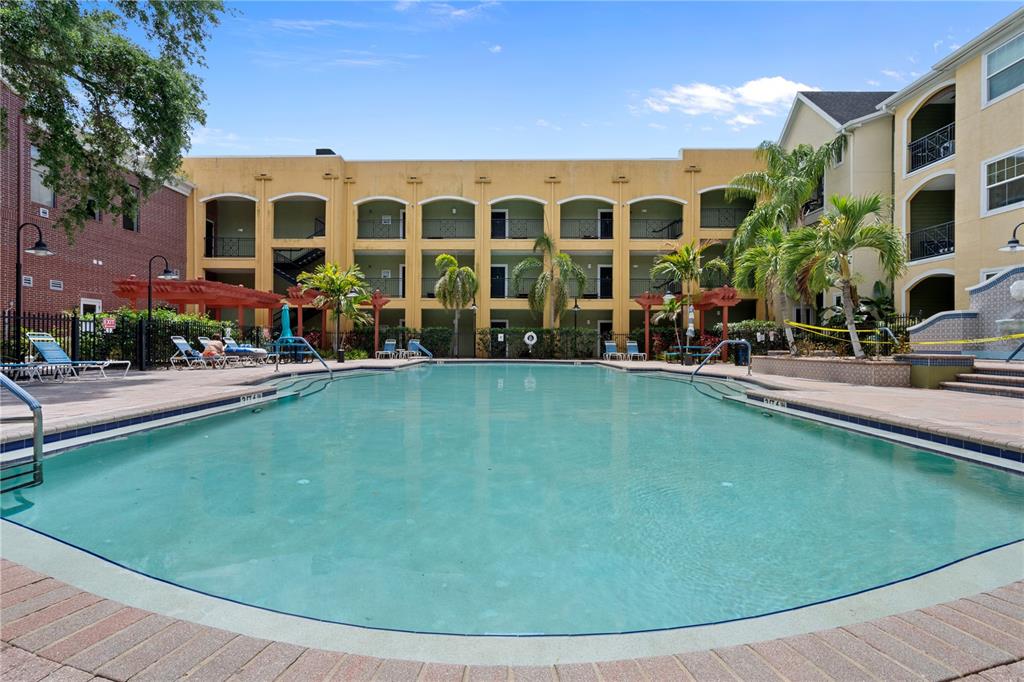 A swimming pool sits in front of a multi-story apartment building with arched balconies — 1810 E PALM AVENUE UNIT 5122, TAMPA, FL