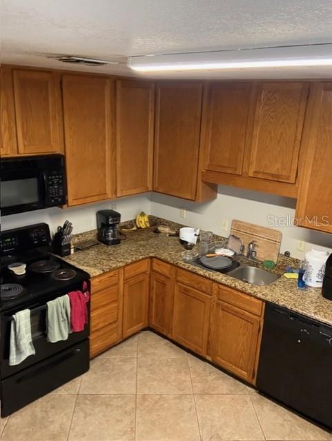 A kitchen with wood cabinets, granite countertops, and black appliances — 1203 CLUBSIDE DRIVE UNIT 1203, LONGWOOD, FL