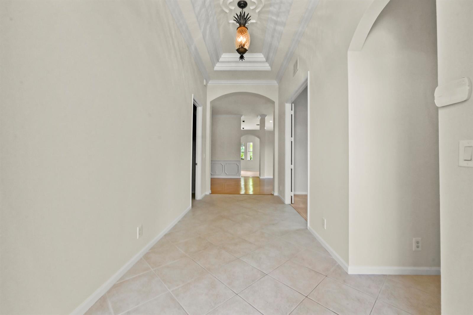 A tiled hallway features a tray ceiling with a pineapple-shaped pendant light — 1488 SE Legacy Cove Circle, Stuart FL 34997, STUART, FL