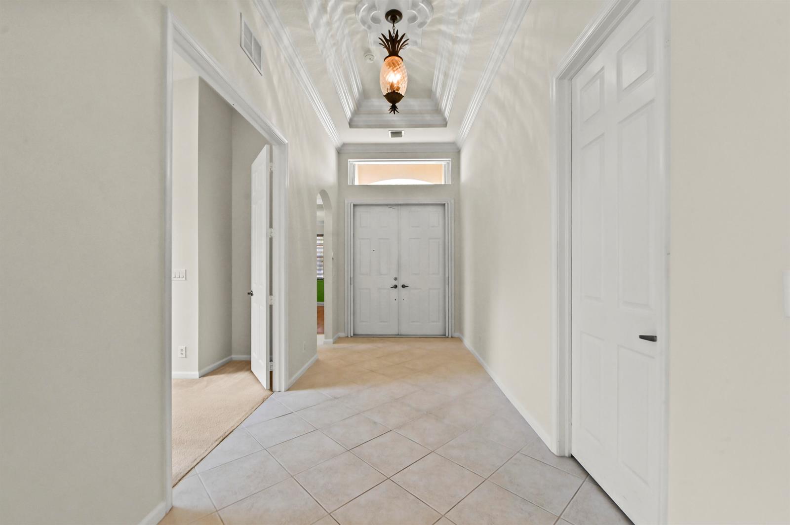 An entryway features a tray ceiling, a pineapple-style pendant light, and light-colored tile flooring — 1488 SE Legacy Cove Circle, Stuart FL 34997, STUART, FL