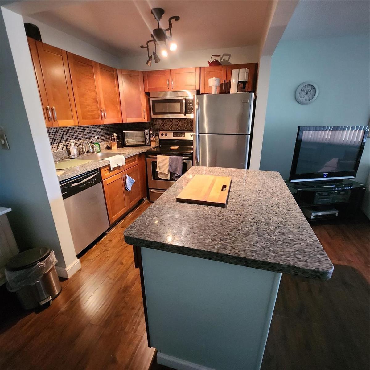 A kitchen with wood cabinets, stainless steel appliances, and a granite-topped island — 198 Durham D, Deerfield Beach FL 33442, DEERFIELD BEACH, FL