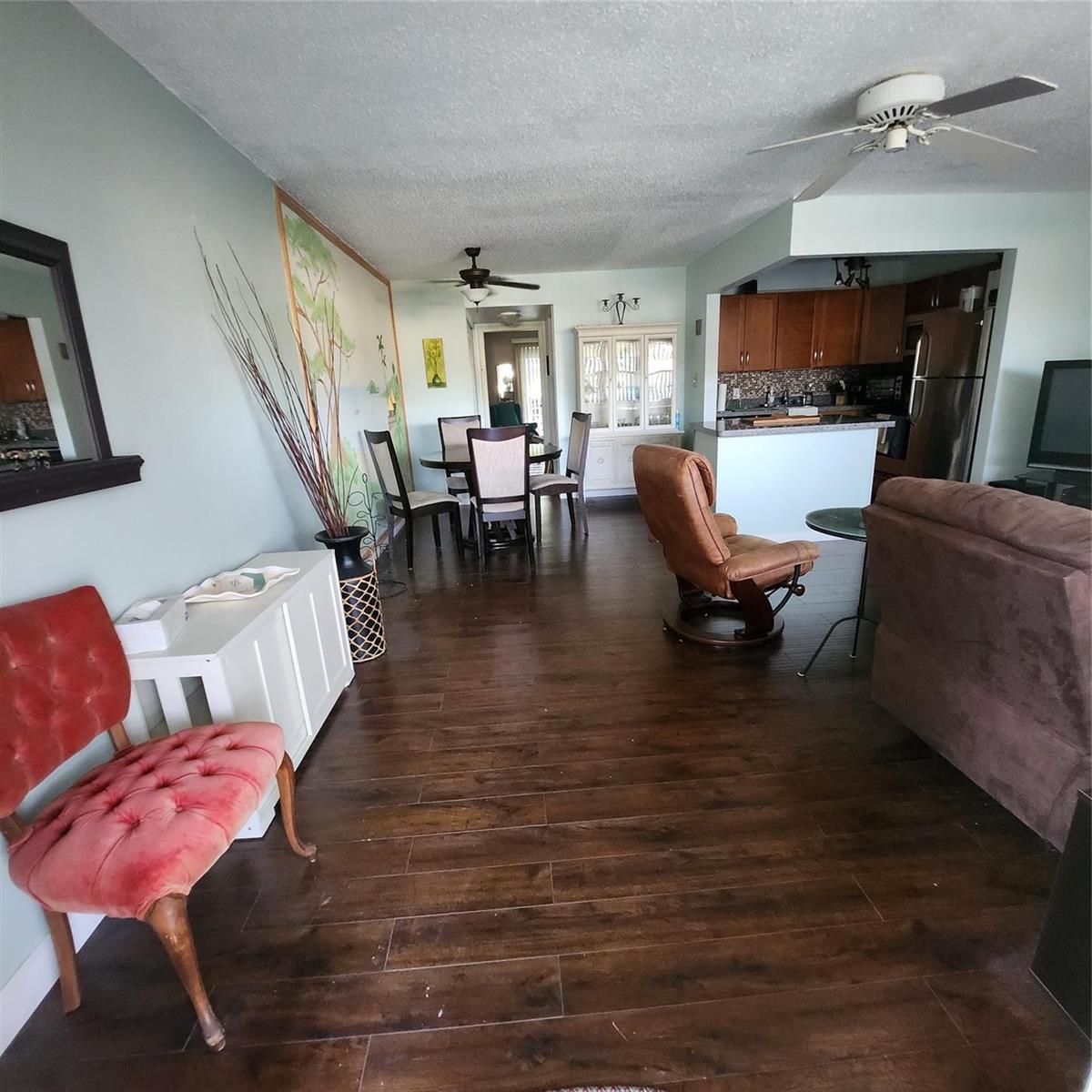An open-concept living and dining area features dark wood flooring, light walls, and kitchen access — 198 Durham D, Deerfield Beach FL 33442, DEERFIELD BEACH, FL