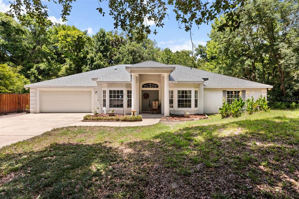 A single-story house with a white exterior, a two-car garage, and a columned entryway — 1420 MIRKWOOD COVE, OVIEDO, FL