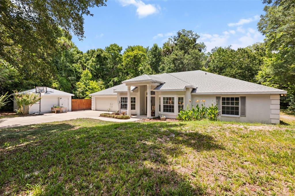 A single-story house with a detached garage and a large front yard surrounded by trees — 1420 MIRKWOOD COVE, OVIEDO, FL
