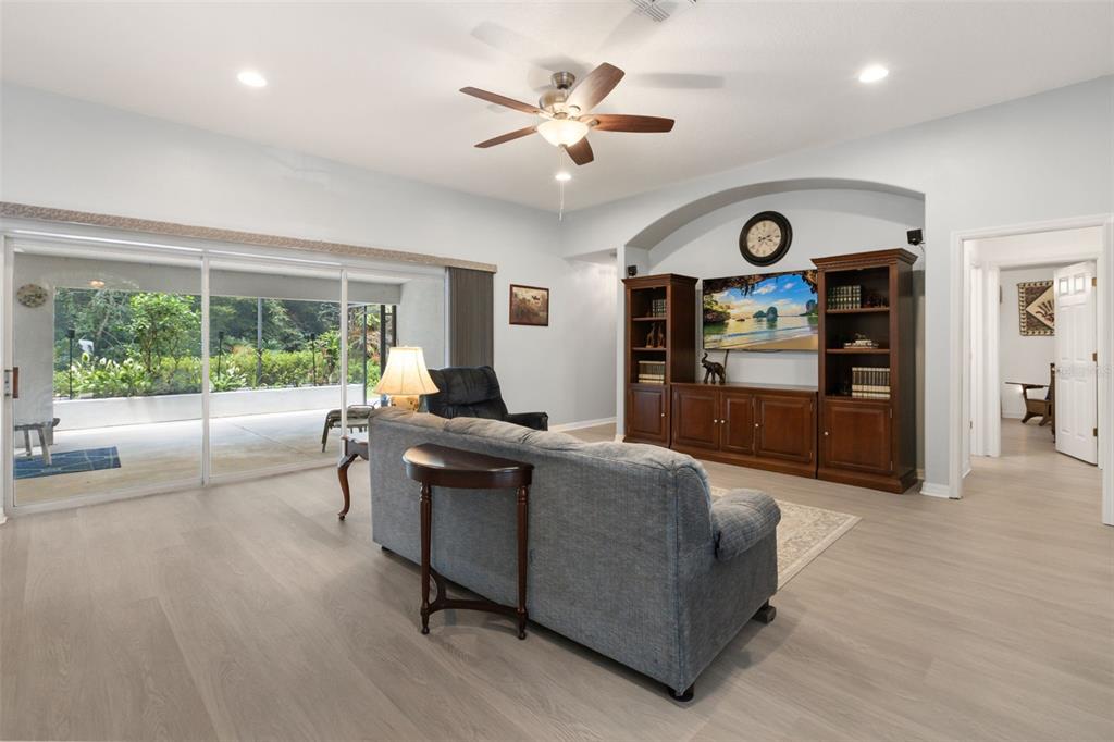 A living room features light wood-look flooring, a ceiling fan, and a built-in media center — 1420 MIRKWOOD COVE, OVIEDO, FL