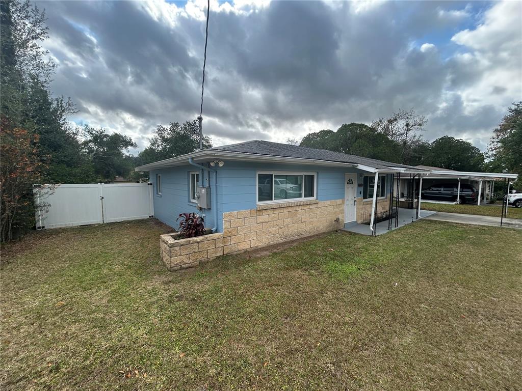 A single-story house with blue siding, a stone facade, and a white vinyl fence — 21570 SW RAINTREE STREETS, DUNNELLON, FL