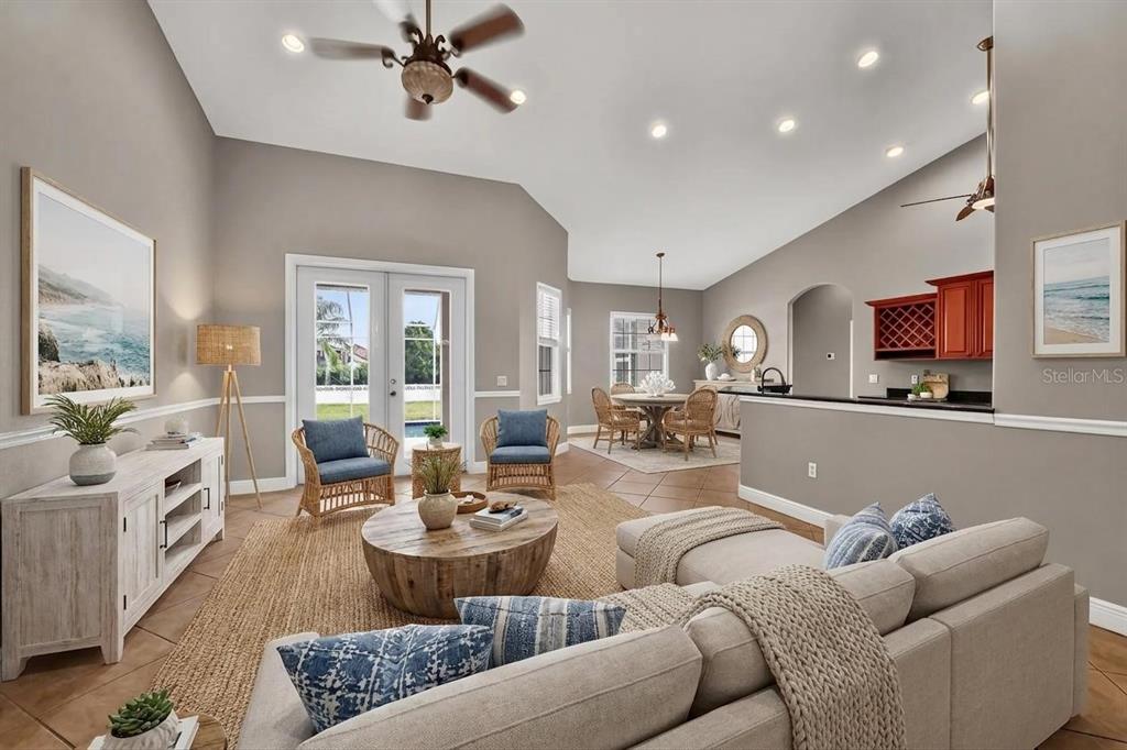 A living room with vaulted ceilings, a beige sectional, a round wooden table, and tile flooring — 16323 UPPER MANATEE RIVER ROAD, BRADENTON, FL