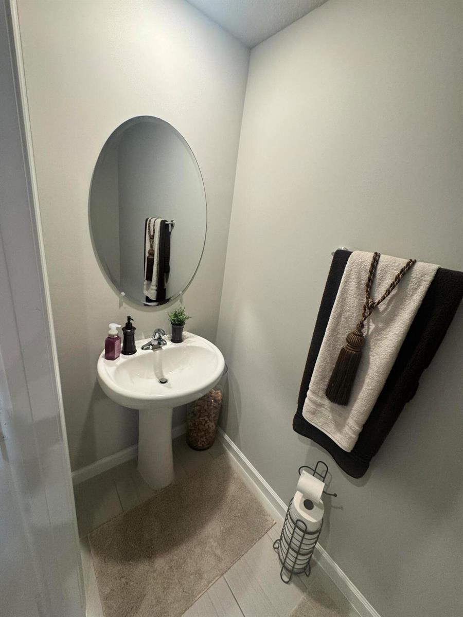 A small powder room features a pedestal sink, an oval mirror, and a towel rack — 526 Salisbury Circle, Fort Pierce FL 34982, FORT PIERCE, FL