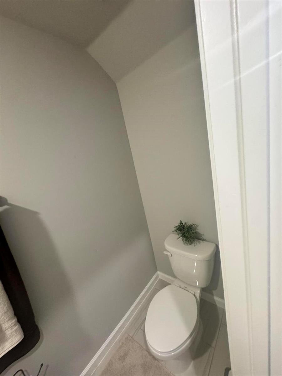 A small bathroom features a white toilet against light gray walls and tiled flooring — 526 Salisbury Circle, Fort Pierce FL 34982, FORT PIERCE, FL