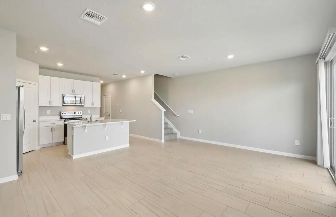 An open-concept kitchen and living area featuring white cabinets, a kitchen island, and tile flooring — 526 Salisbury Circle, Fort Pierce FL 34982, FORT PIERCE, FL