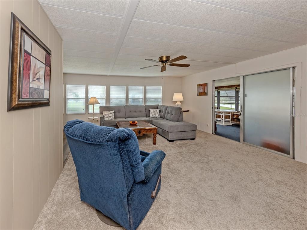 A living room features a blue recliner, a gray sectional sofa, and a sliding glass door — 222 SCHOONER STREET, NORTH PORT, FL
