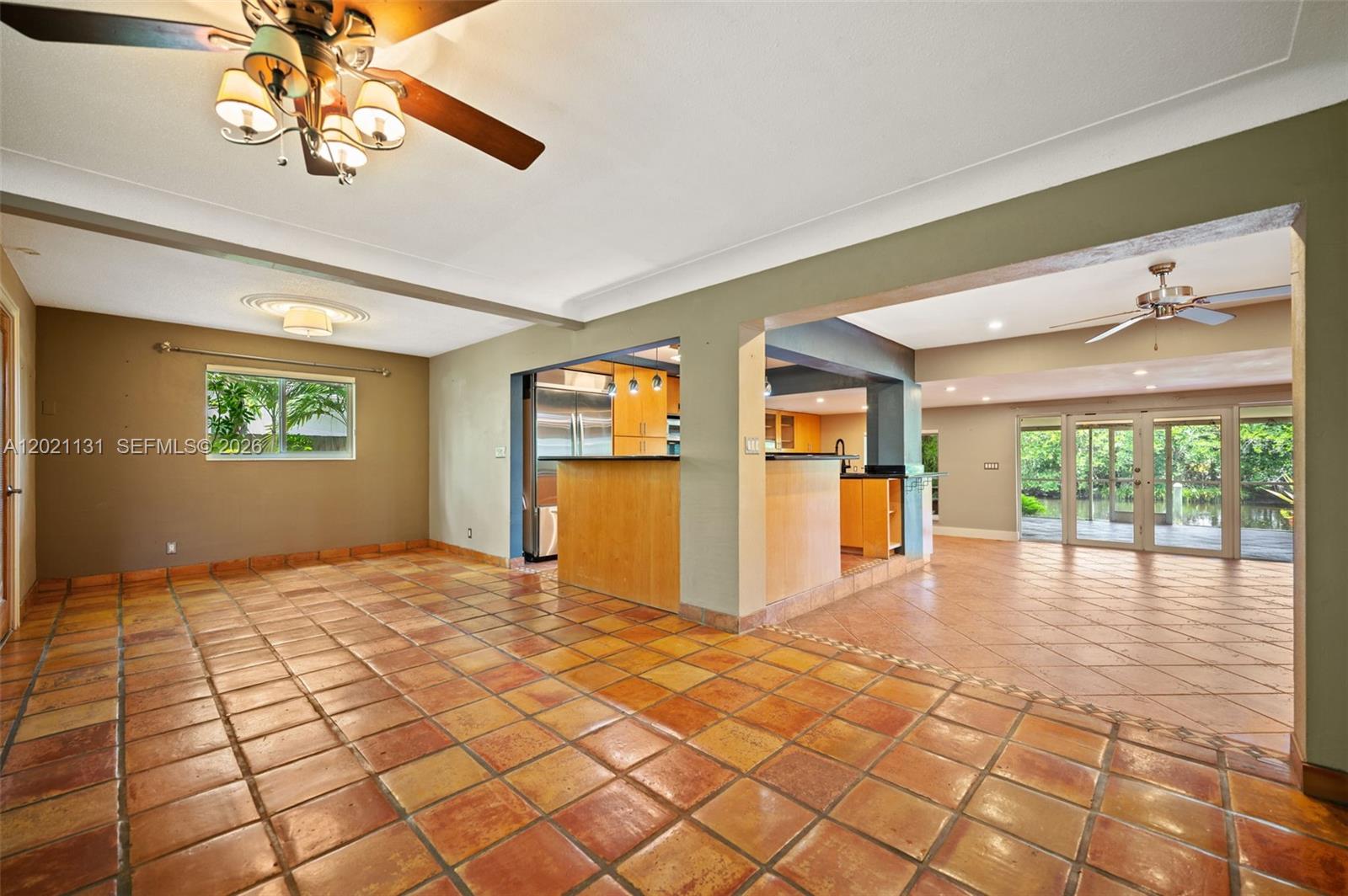 An open-concept living and kitchen area features terracotta tile flooring and two ceiling fans — 4512 SW 37th Ave, Dania Beach FL 33312, DANIA BEACH, FL