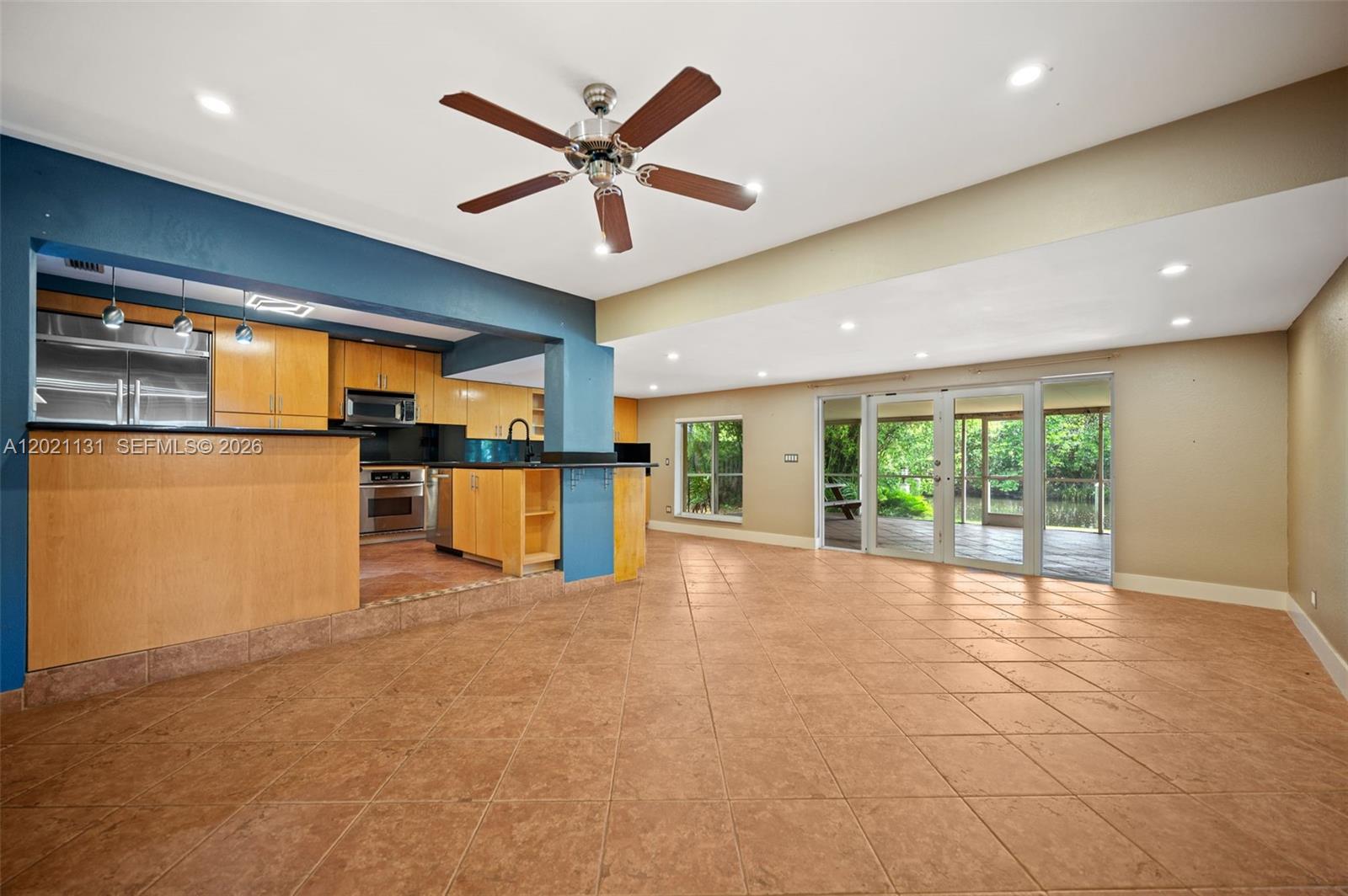 An open-concept living area features tile flooring, a blue-accented kitchen, and sliding glass doors — 4512 SW 37th Ave, Dania Beach FL 33312, DANIA BEACH, FL