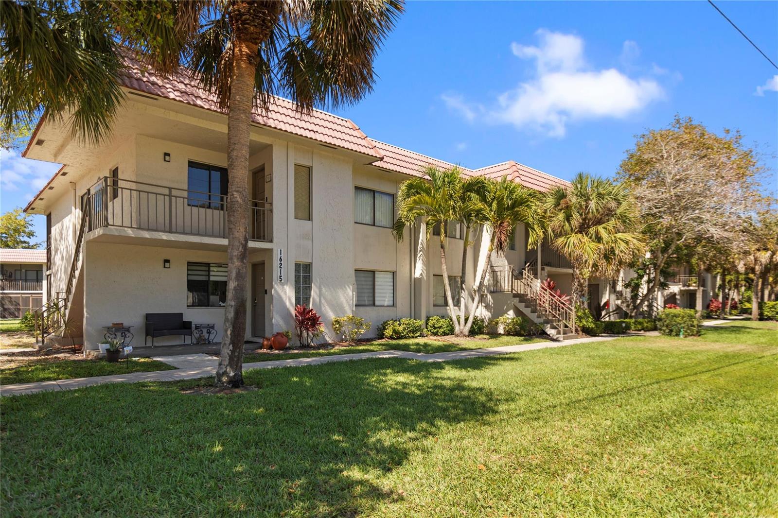 A two-story apartment building with a tiled roof, balconies, and palm trees on a lawn — 16211 Saddle Club Road # 102, Weston FL 33326, WESTON, FL