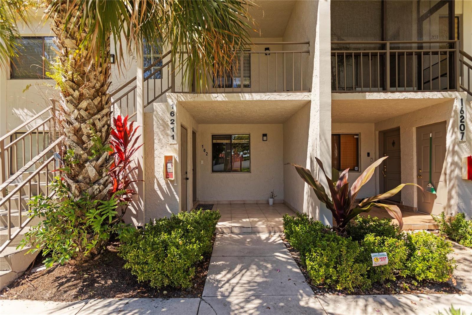 Exterior view of two-story apartment units with a shared walkway, stairs, and landscaping — 16211 Saddle Club Road # 102, Weston FL 33326, WESTON, FL