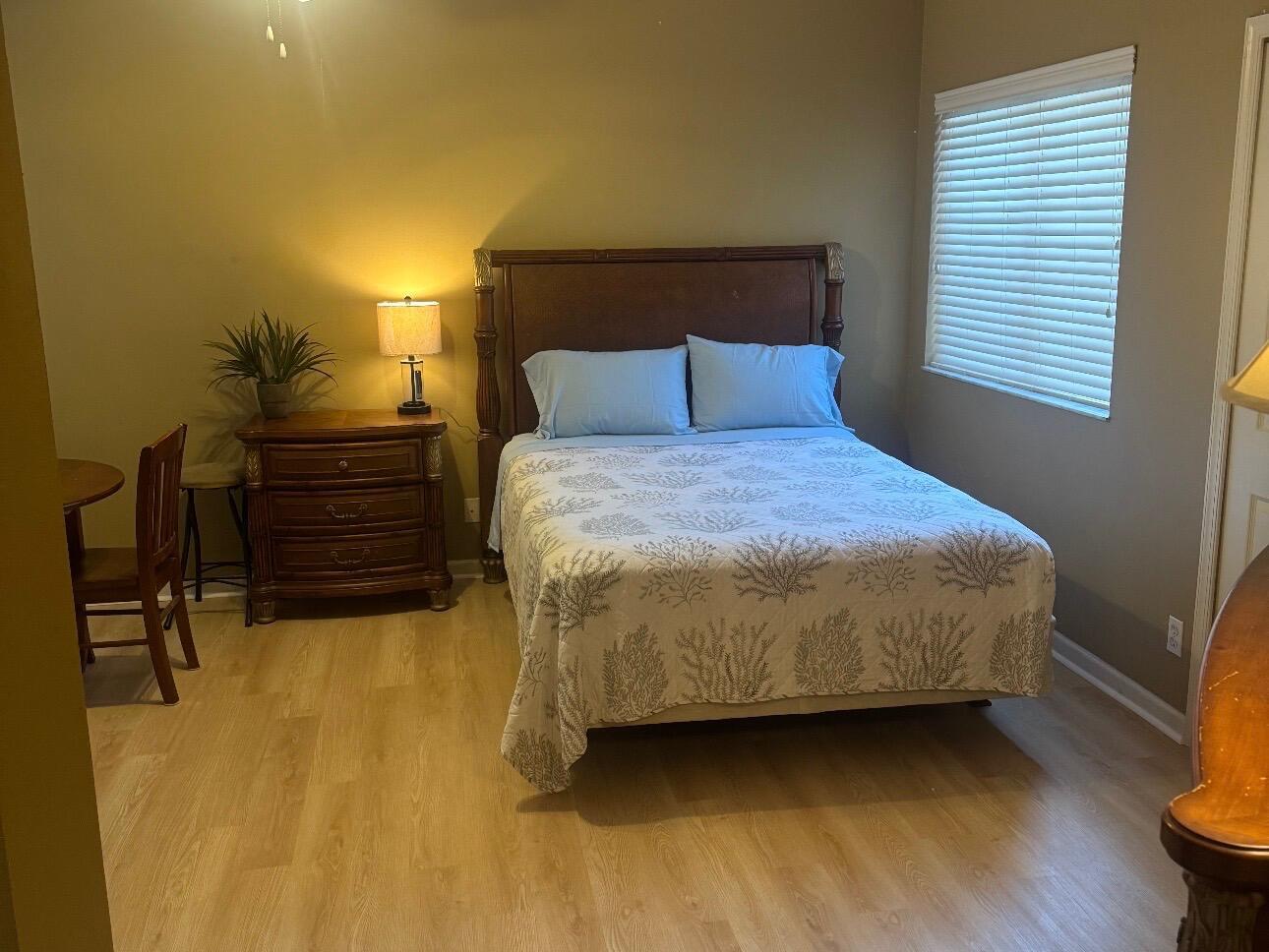 A bedroom features a wooden bed frame, a nightstand with a lamp, and light flooring — 8910 Sandshot Court # 5123, FL 34986, FL