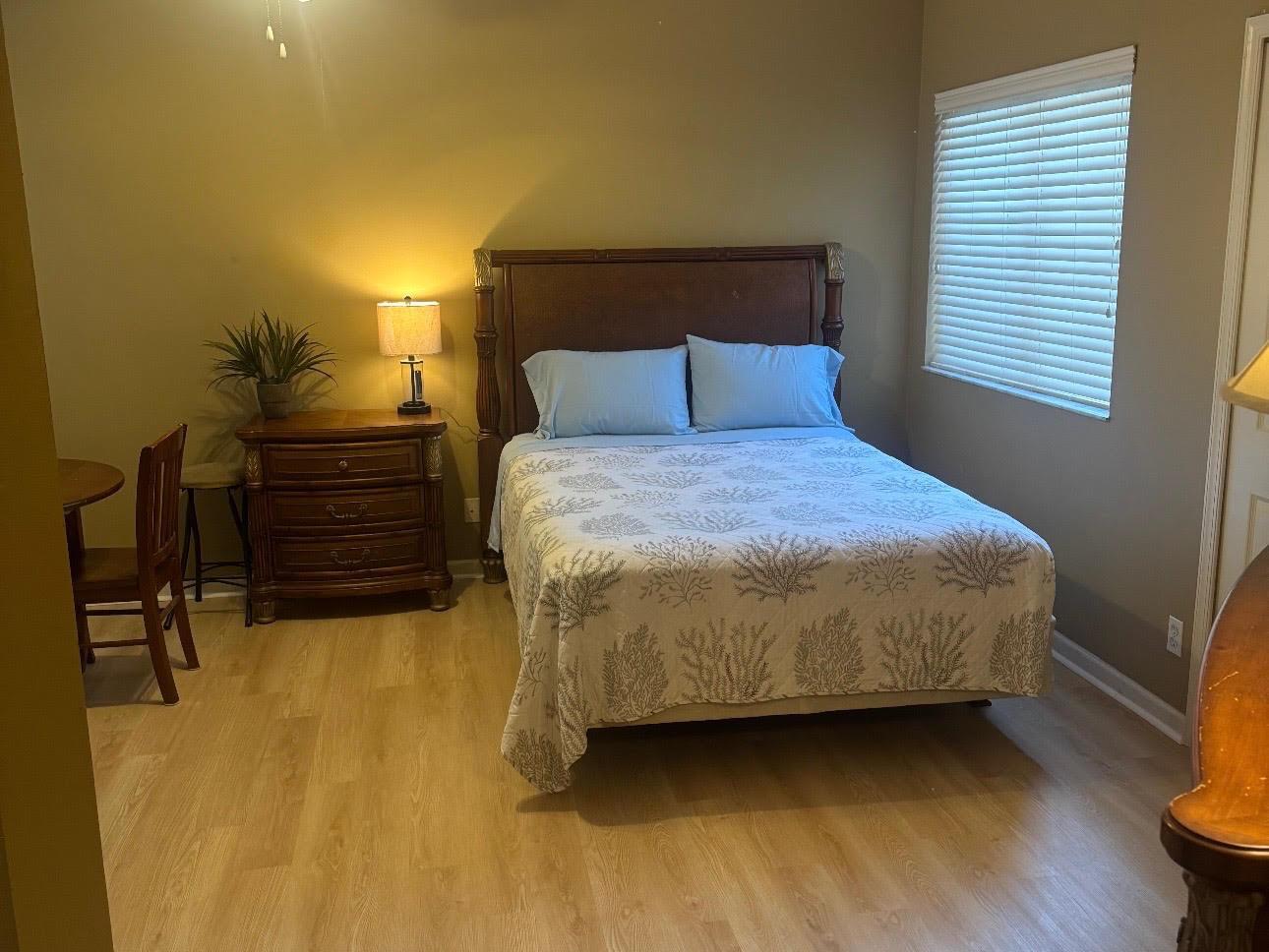 A bedroom features a wooden bed frame, a nightstand with a lamp, and light flooring — 8910 Sandshot Court # 5123, FL 34986, FL