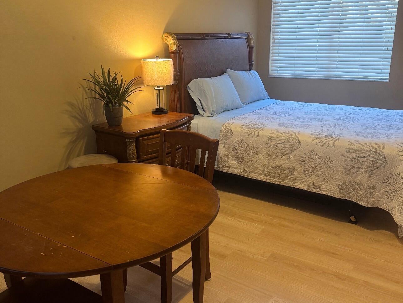 A bedroom features a wooden bed frame, a round dining table, and a bedside lamp — 8910 Sandshot Court # 5123, FL 34986, FL
