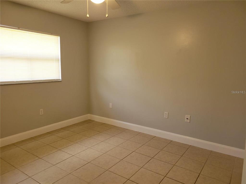An empty bedroom features light gray walls, beige tile flooring, and a single window — 807 MCLAIN COURT, TAVARES, FL