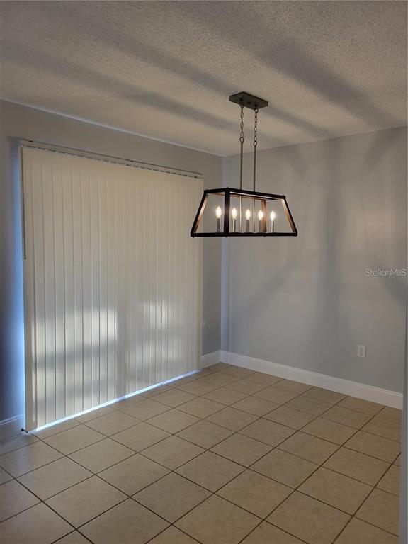 A dining area features light gray walls, beige tile flooring, and a modern rectangular chandelier — 807 MCLAIN COURT, TAVARES, FL