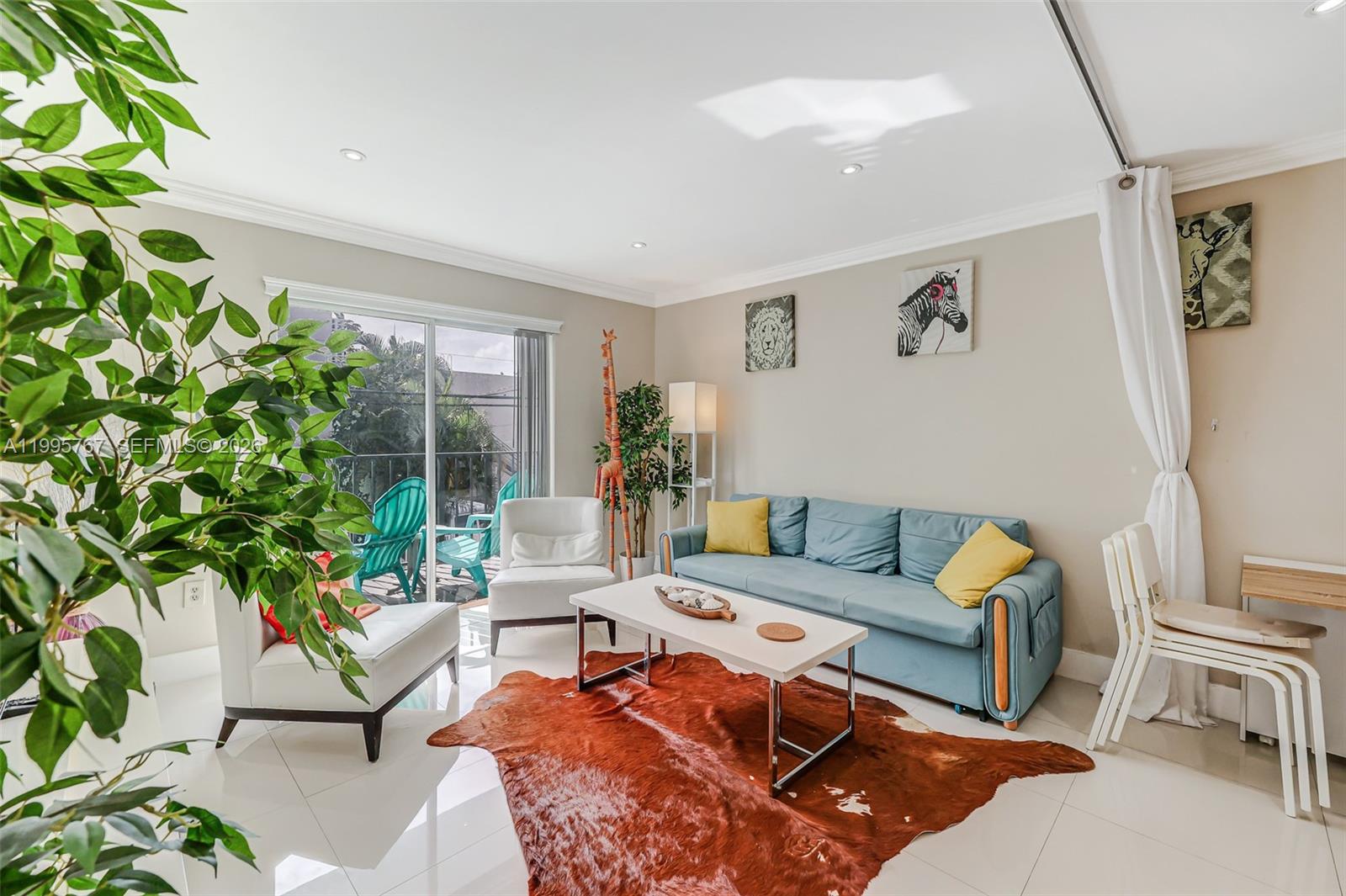 A living room features a blue sofa, white chairs, a cowhide rug, and a balcony — 618 Euclid Ave # 204, Miami Beach FL 33139, MIAMI BEACH, FL