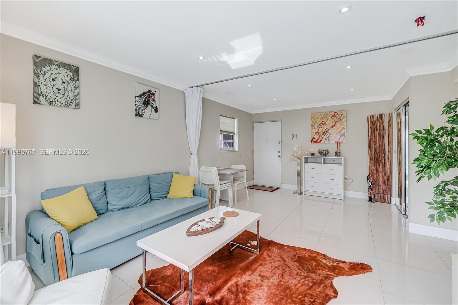 A living room features a blue sofa, white coffee table, and a brown cowhide rug — 618 Euclid Ave # 204, Miami Beach FL 33139, MIAMI BEACH, FL