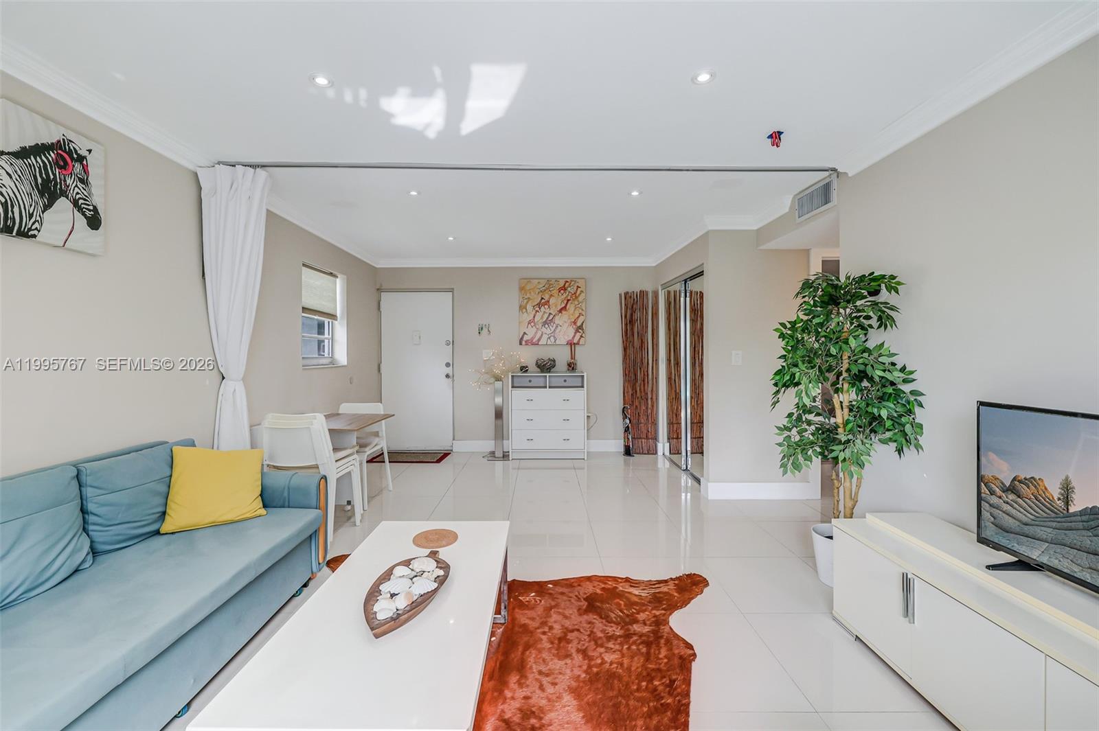 A living room features a blue sofa, white coffee table, cowhide rug, and tile flooring — 618 Euclid Ave # 204, Miami Beach FL 33139, MIAMI BEACH, FL
