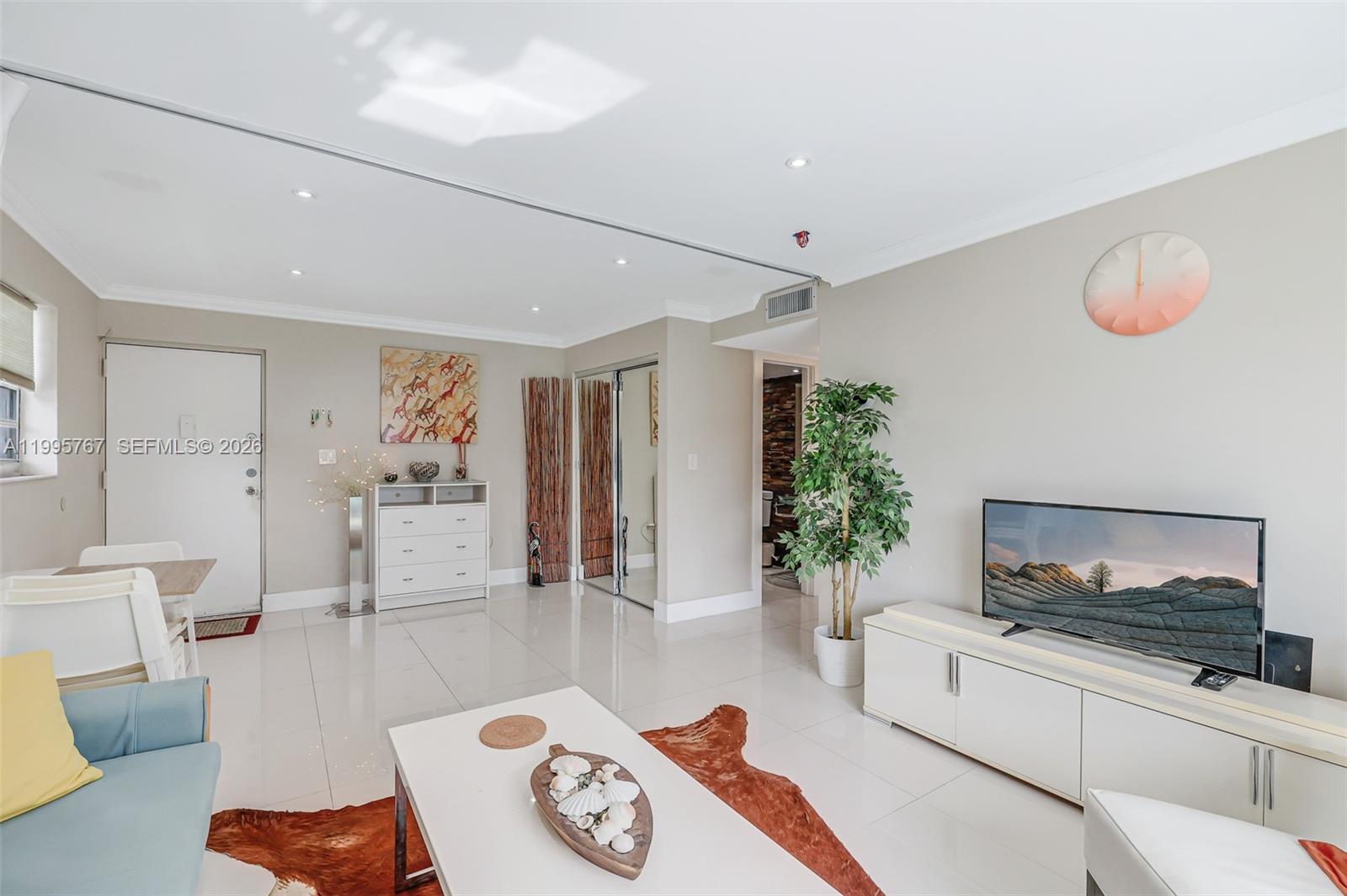 A living room features white tile floors, a television, a coffee table, and a rug — 618 Euclid Ave # 204, Miami Beach FL 33139, MIAMI BEACH, FL