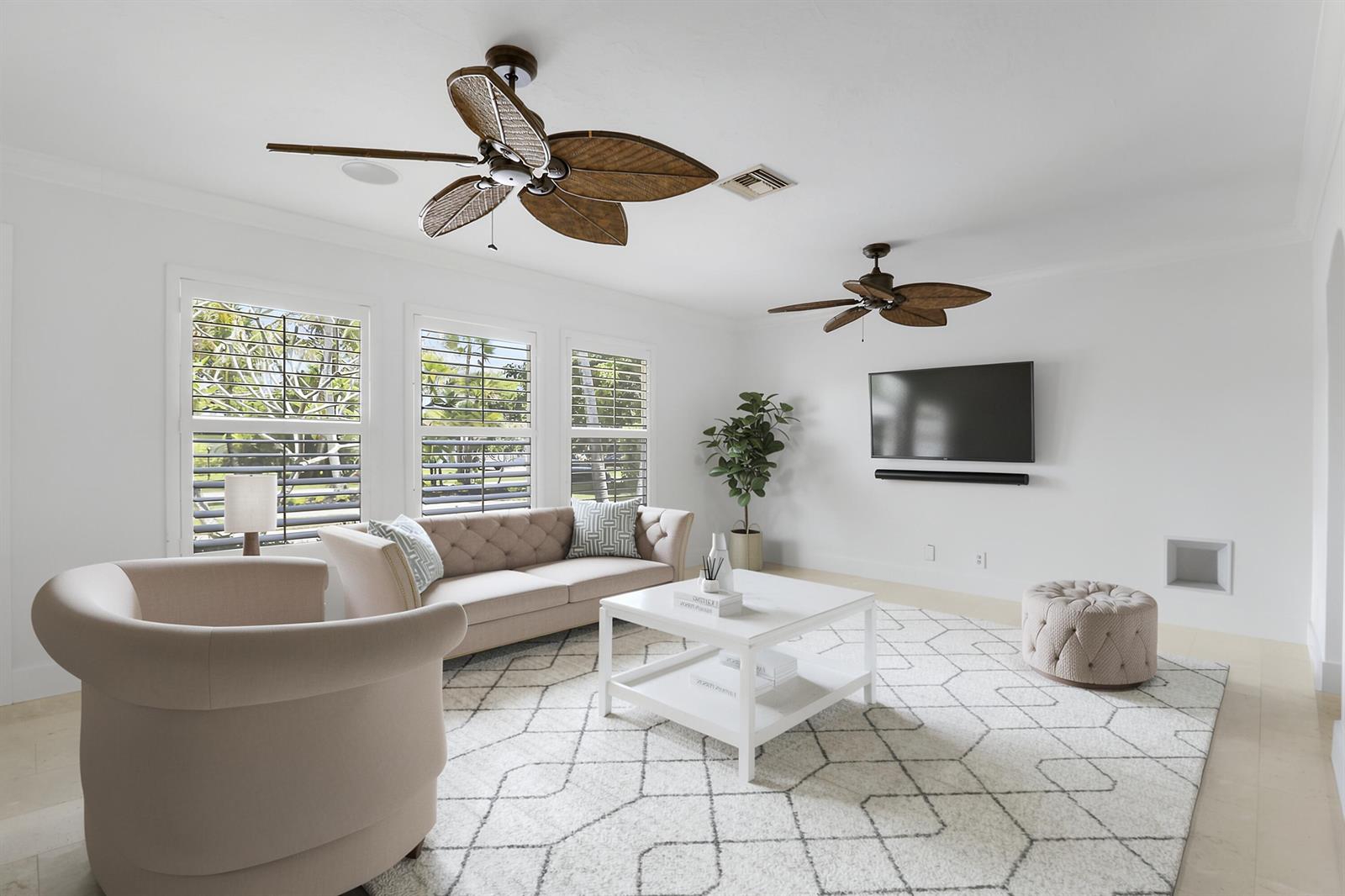 A bright living room features two tropical-style ceiling fans, a beige sofa, and white furniture — 19931 Jasmine Drive, Jupiter FL 33469, JUPITER, FL