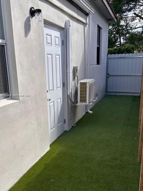 A white exterior wall features a door, an outdoor light, and a wall-mounted air conditioner — 5180 NW 14th Ave # B, Miami FL 33142, MIAMI, FL