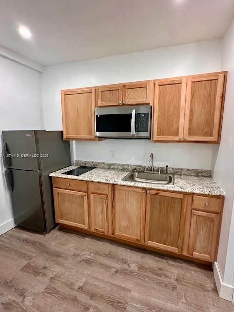 A kitchen features light wood cabinets, granite countertops, a stainless steel microwave, and a refrigerator — 5180 NW 14th Ave # B, Miami FL 33142, MIAMI, FL