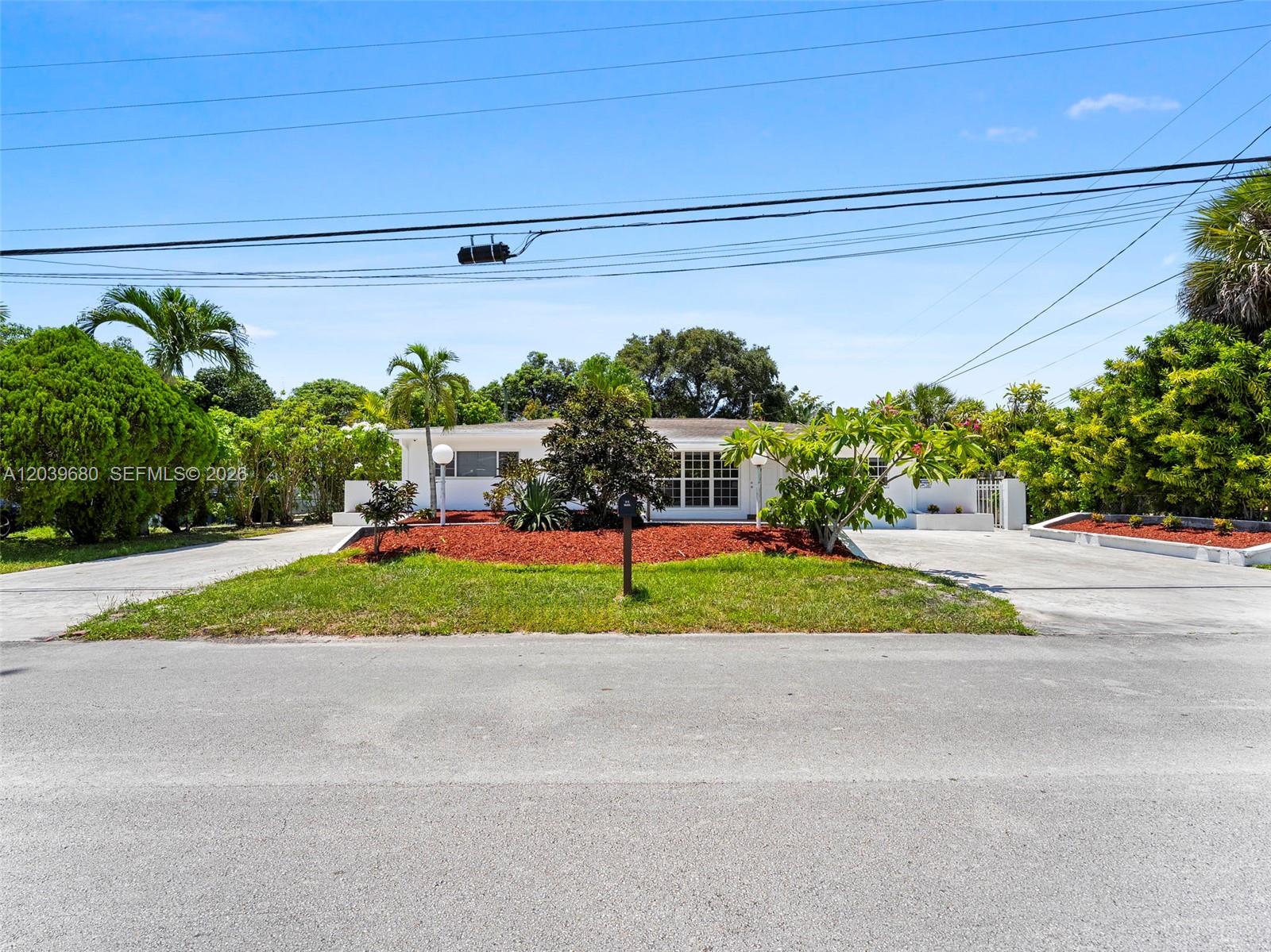 A single-story white house features a circular driveway and a landscaped front yard — 110 NE 152nd St, Miami FL 33162, MIAMI, FL
