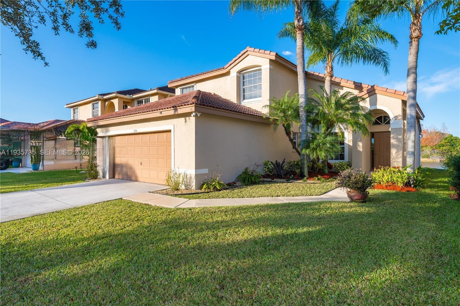 A two-story suburban house with a tan stucco exterior, tile roof, and attached garage — 2824 SW 183rd Ave, Miramar FL 33029, MIRAMAR, FL