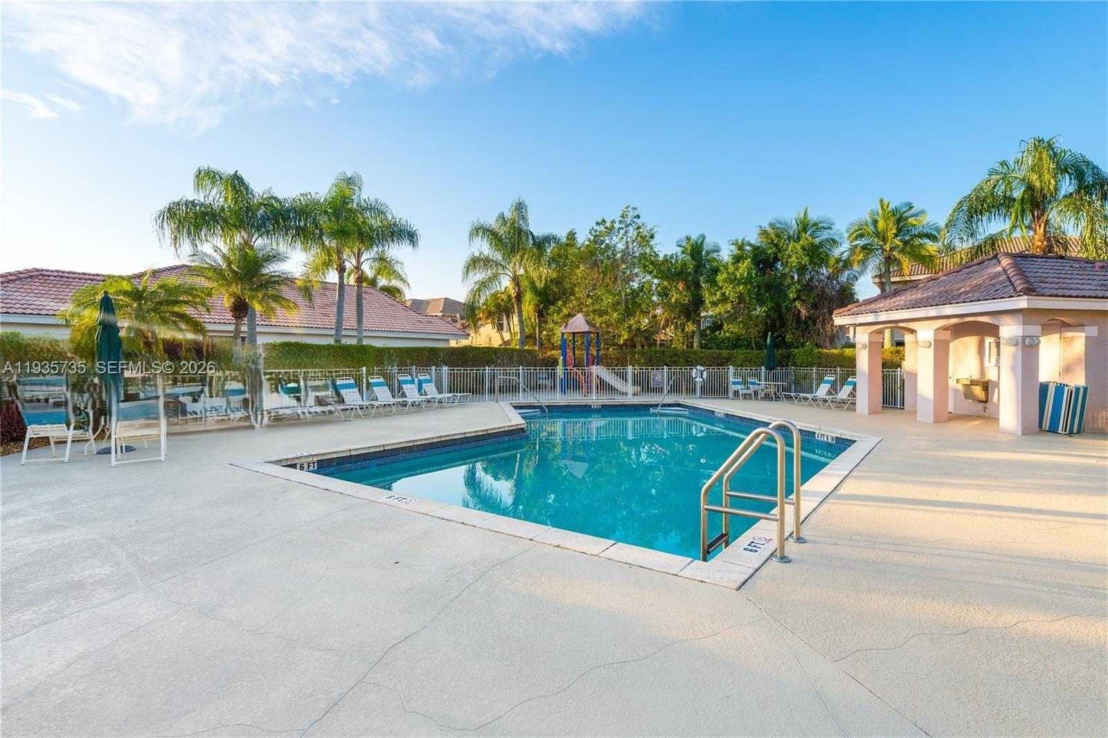A rectangular swimming pool sits on a concrete deck surrounded by lounge chairs and palm trees — 2824 SW 183rd Ave, Miramar FL 33029, MIRAMAR, FL