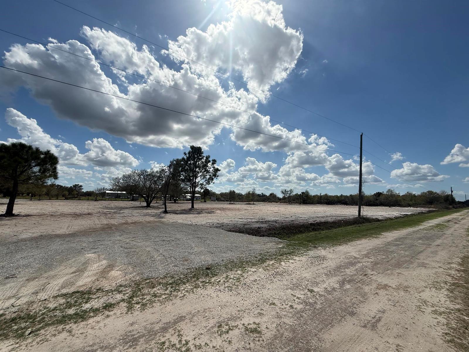 A wide, flat, cleared dirt lot features a few scattered trees under a cloudy sky — 14416 NW 252nd Street, Okeechobee FL 34972, OKEECHOBEE, FL
