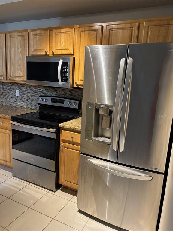 A kitchen features light wood cabinets, stainless steel appliances, and a granite countertop — 5691 BENTGRASS DRIVE UNIT 15-209, SARASOTA, FL