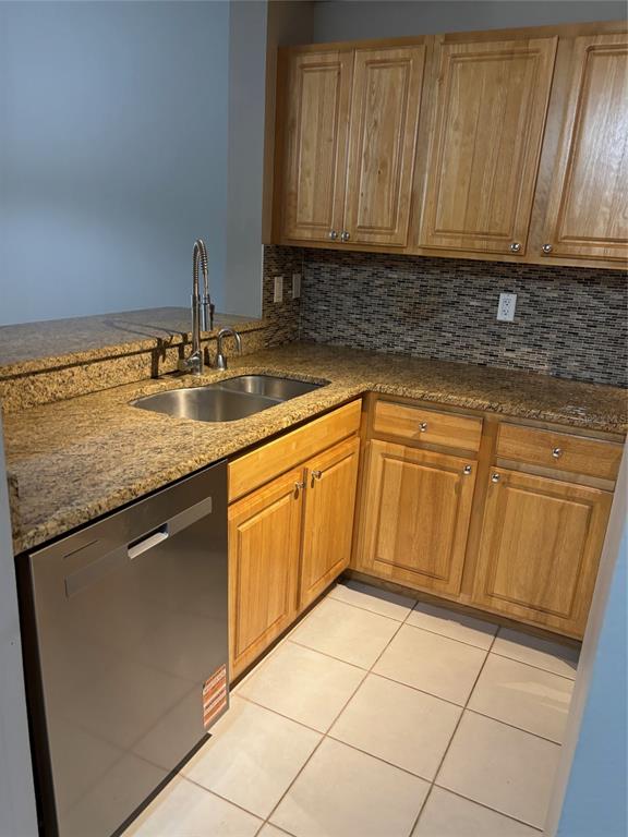 A kitchen features light wood cabinets, granite countertops, a stainless steel dishwasher, and tiled flooring — 5691 BENTGRASS DRIVE UNIT 15-209, SARASOTA, FL