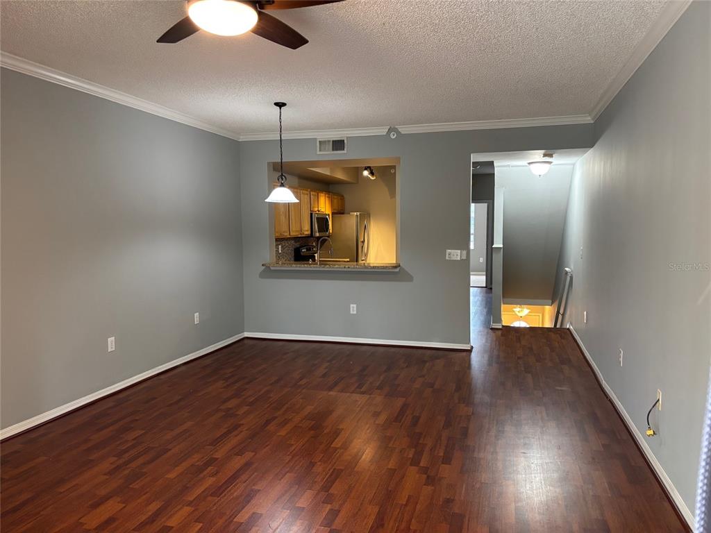 An open living area features dark wood flooring, gray walls, and a kitchen pass-through window — 5691 BENTGRASS DRIVE UNIT 15-209, SARASOTA, FL